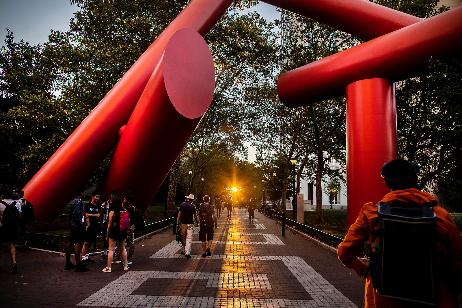 Sunset view of students on Locust Walk, near the Covenant sculpture.
